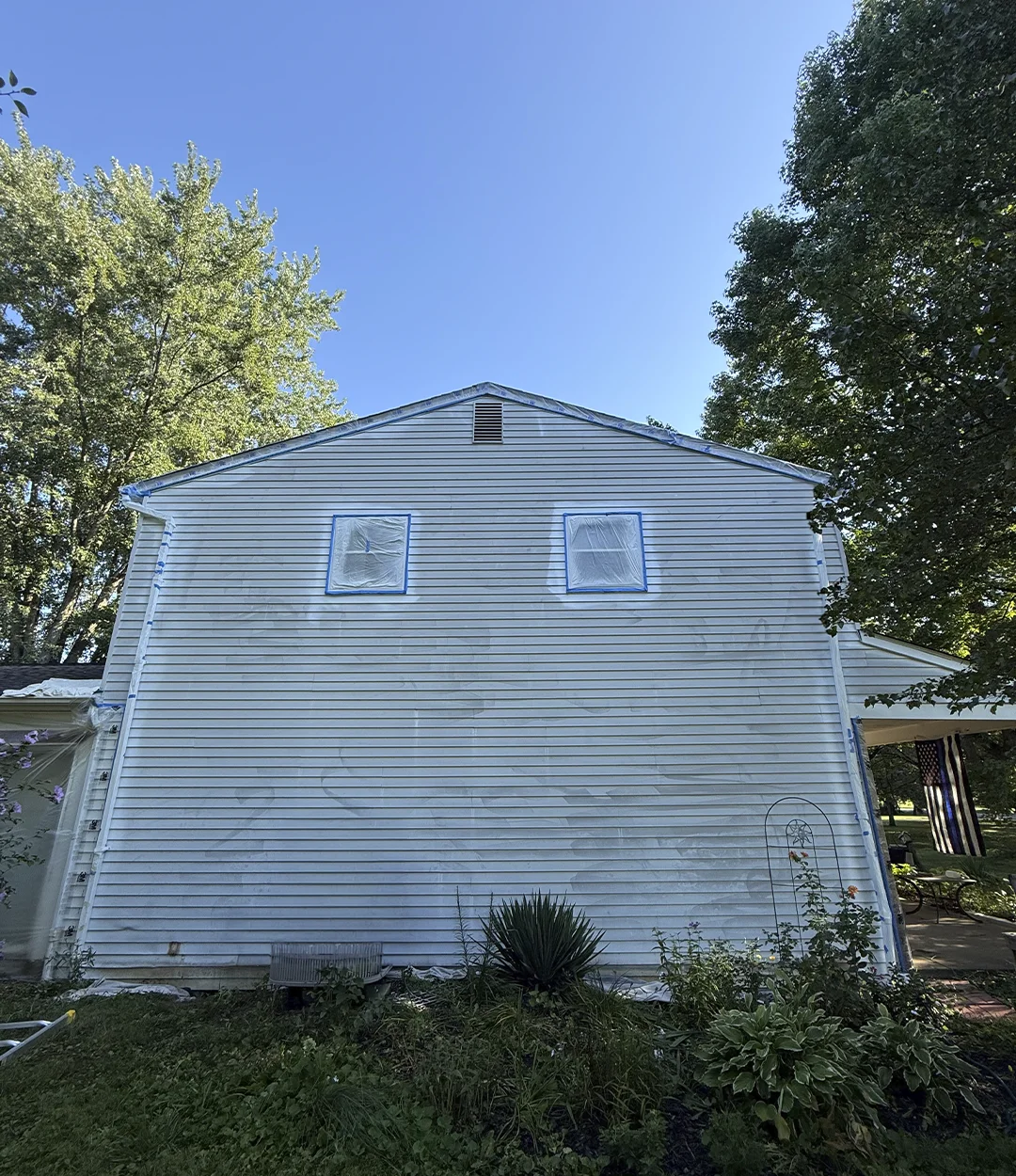 Home siding before painting, windows taped for prep